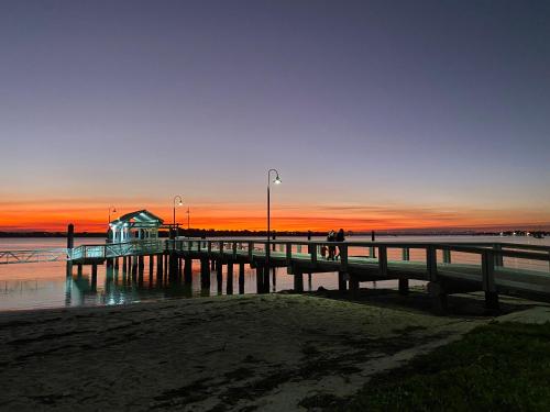 a pier with a person standing on it at sunset at Sylvan Seas in Bellara