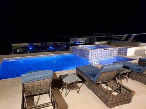 a swimming pool with some chairs and a table at Majestic Beachfront Hideaway in Alisitos