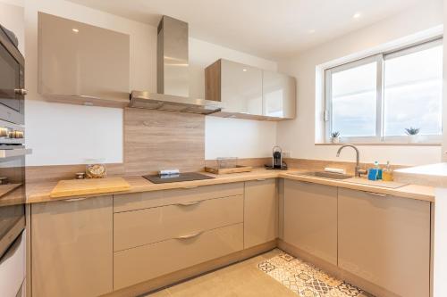 une cuisine avec des armoires en bois, un évier et une fenêtre dans l'établissement Grand 4 pièces 6 personnes fabuleuse vue mer clim garage, à Villeneuve-Loubet