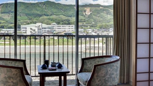 a room with two chairs and a table and a large window at Fukusenka in Ukiha