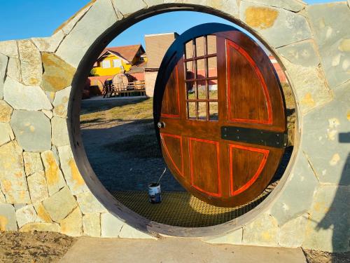 a round mirror with a wooden door in a stone wall at Cabañas EMC in Los Vilos