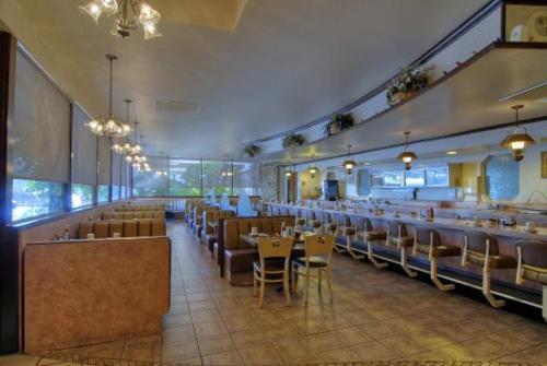 un comedor con mesas y sillas en un restaurante en Duniya Hotel, en Bakersfield