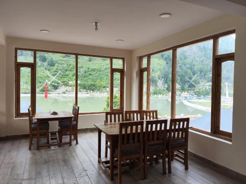 a dining room with a table and chairs and windows at The Kamru Riverside Camps and Resorts in Sāngla