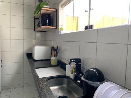 a kitchen with a sink and a microwave at Casa 3 suítes com piscina in Natal