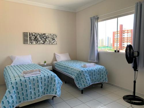 a bedroom with two beds and a window at Casa 3 suítes com piscina in Natal
