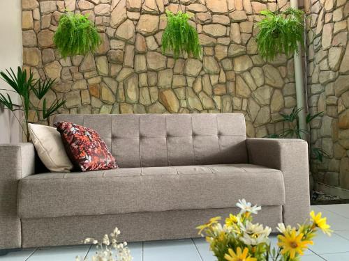 a gray couch with two pillows in front of a stone wall at Casa 3 suítes com piscina in Natal