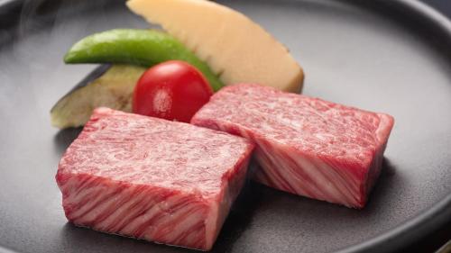 two pieces of meat on a plate with cheese and fruit at Fukusenka in Ukiha