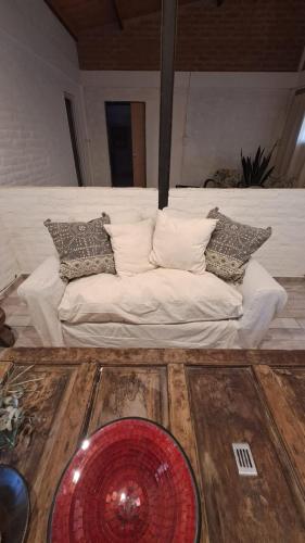 a white couch with pillows on a wooden floor at Rest Home Los Horneros in Santa Ana