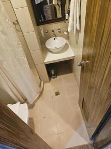 Pacific Bay Grand Suites في مانيلا: حمام صغير مع حوض ومرحاض