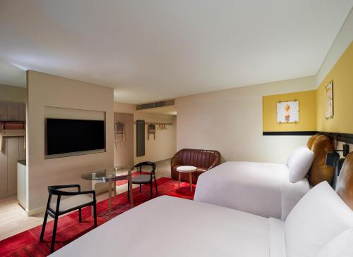 Moxy Seoul Myeongdong في سول: غرفة فندق بسرير وتلفزيون
