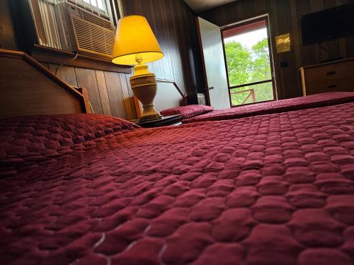 a bedroom with a bed with a lamp and a window at The Gold Eagle in Lake George