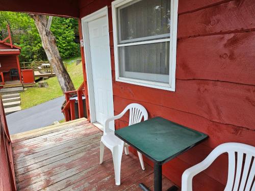 a red house with a table and chairs on a porch at The Gold Eagle in Lake George