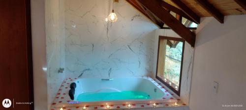 ein Bad mit blauer Badewanne in einem Zimmer mit Fenster in der Unterkunft Pousada Solard'isabell in Monte Verde