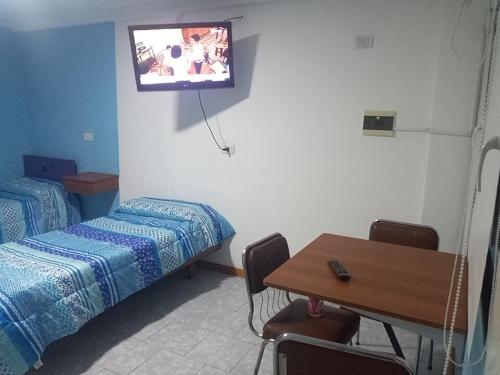 a room with a bed and a table with a tv on the wall at 365 Dptos in Villa Regina