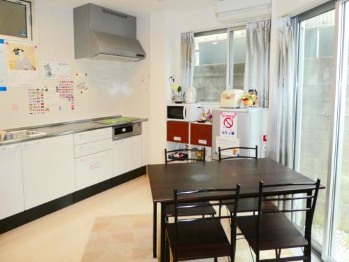a kitchen with a table and chairs and a refrigerator at Guest House Ochakare in Kanazawa