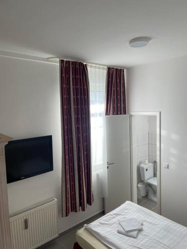 a room with a bed and a television and a bathroom at Pension-Wob 2 in Wolfsburg