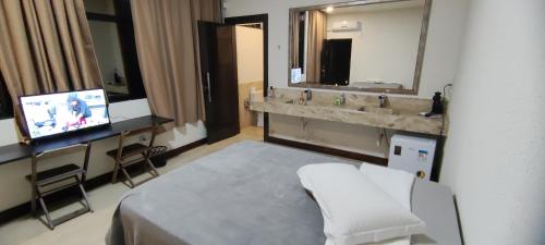 a bathroom with a bed and a sink and a television at Pousada Sol in Pato Branco