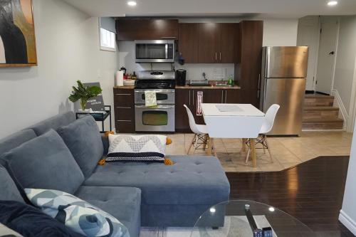 uma sala de estar com um sofá azul e uma cozinha em Patio privé, hébergement équipé et spacieux. em Hamilton