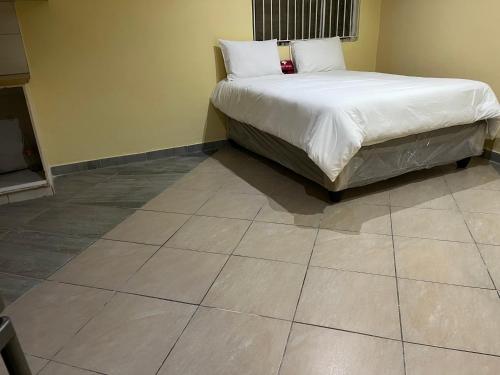 a bedroom with a bed and a tiled floor at Eldos Guest House in Soweto