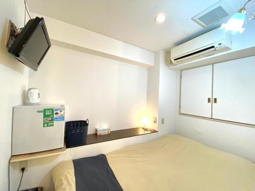 Habitación pequeña con cama y TV. en Tabist Hotel Aurora Ikebukuro en Tokio
