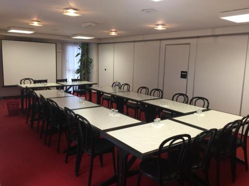 a row of tables and chairs in a room at The Originals City, Hôtel Éden, Rouen Nord in Bois-Guillaume