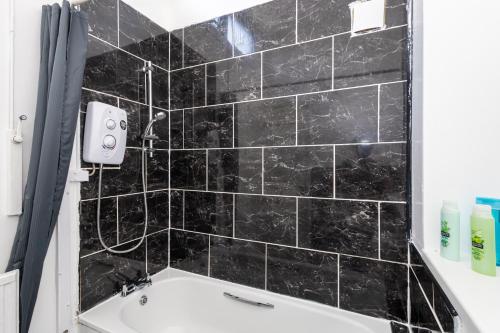 a bathroom with black tiled walls and a bath tub at Large House Contractors Leisure Near Old Trafford in Manchester
