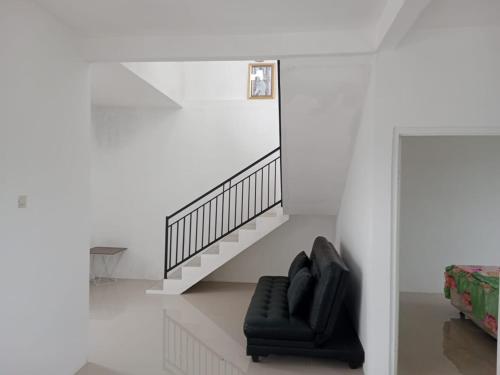 Una silla negra en una habitación blanca con una escalera en APUT VILLA RESIDENCE MUTIARA B7, en Songgoriti