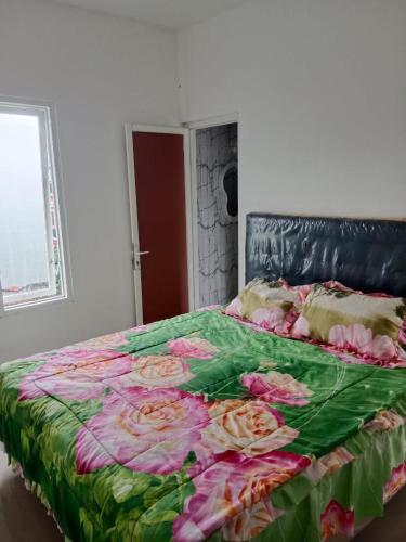 Una cama con una manta verde y rosa. en APUT VILLA RESIDENCE MUTIARA B7, en Songgoriti