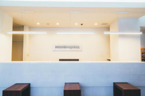 two benches sitting in a waiting room with lights at Quintessa Hotel Kokura Comic & Books in Kitakyushu