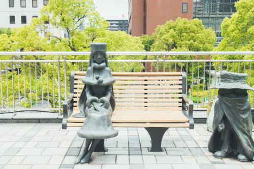two statues of people sitting on a bench at Quintessa Hotel Kokura Comic & Books in Kitakyushu