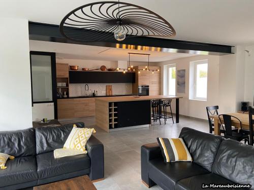 un salon avec un canapé et une cuisine dans l'établissement Séjour de charme à Mareau-aux-Bois : parc, home cinéma, billard, tennis et télétravail en fibre ultra-rapide - FR-1-590-279, à Mareau-aux-Bois