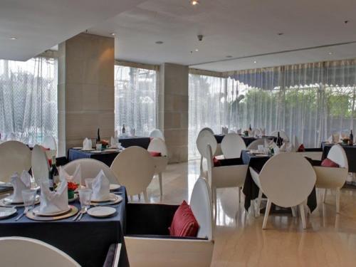 a dining room with tables and white chairs and tablesearcher at Svenska Design Hotel, Electronic City, Bangalore in Bengaluru