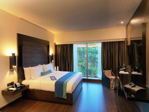 Habitación de hotel con cama y TV en Svenska Design Hotel, Electronic City, Bangalore, en Bangalore