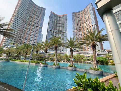 een zwembad met palmbomen en hoge gebouwen bij Gold Coast Sea View Apartments by Rentrooms in Jakarta