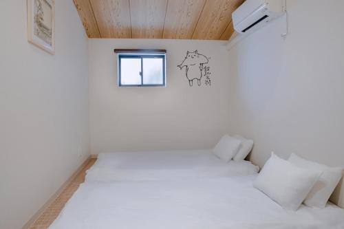 a bedroom with a white bed and a window at 桜の宿 in Osaka