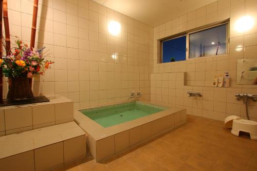 La salle de bains est pourvue d'une baignoire avec un vase de fleurs. dans l'établissement Dainichiya-ryokan, à Sasaguri