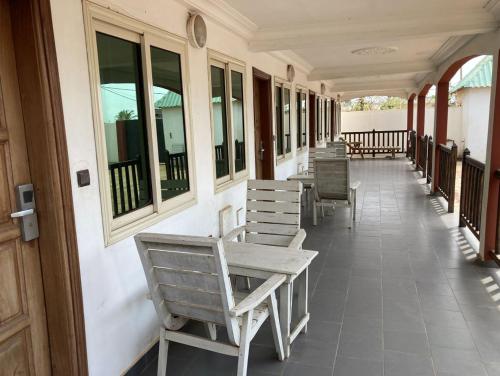 una fila di sedie seduta sul portico di un edificio di Hotel Bel Azur Hillacondji a Hila-Kondji