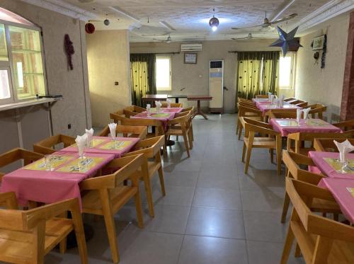 una sala da pranzo con tavoli rosa e sedie in legno di Hotel Bel Azur Hillacondji a Hila-Kondji