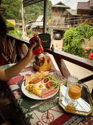 a table with a plate of food with eggs and toast at บ้านพักกึ๊ดเติง แม่กำปอง เชียงใหม่ in Mae On
