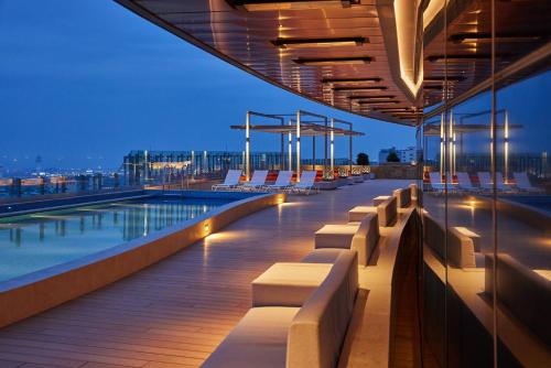 a rooftop deck with chairs and a pool at night at Lotte City Hotel Jeju Airport in Jeju