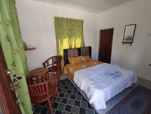 a small bedroom with a bed and two chairs at Man Homestay in Kampong Bukit China