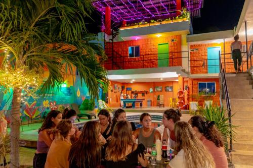 a group of people sitting at a table in front of a building at Hostel Nirvana Taganga in Taganga