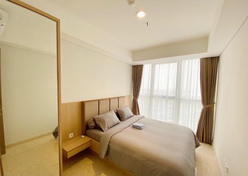 een slaapkamer met een groot bed en een spiegel bij Gold Coast Sea View Apartments by Rentrooms in Jakarta