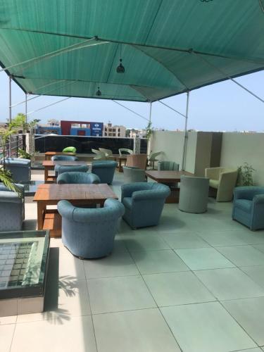 un patio con mesas, sillas y una sombrilla verde en Hotel Bel Azur Cotonou, en Cotonou