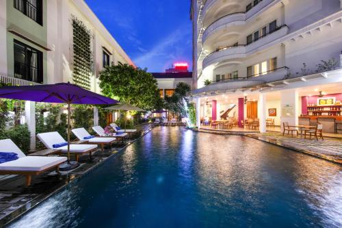 a hotel pool with chairs and umbrellas at night at ÊMM Hotel Hue in Hue