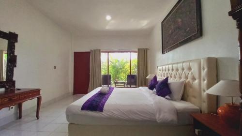 a bedroom with a bed and a desk and a window at Matahari Inn Kuta Lombok in Kuta Lombok
