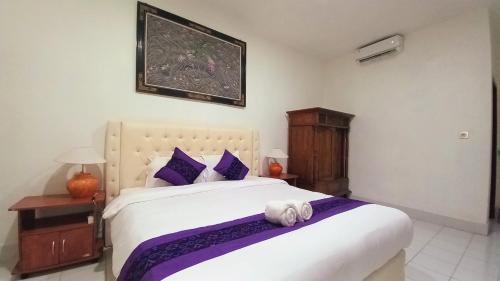 a bedroom with a large white bed with purple pillows at Matahari Inn Kuta Lombok in Kuta Lombok