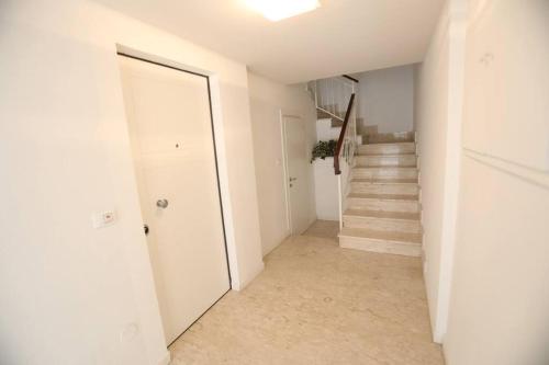 un pasillo con paredes blancas y escaleras con puerta en Casa Magenta Apartment 1, en Valeggio sul Mincio