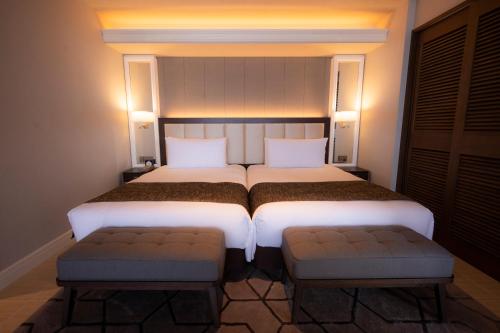 a bedroom with two beds and two seats at Hiyori Ocean Resort Okinawa in Onna