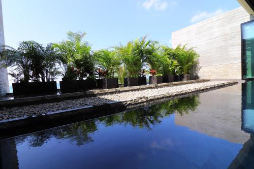 a pool of water with palm trees in front of a building at Hiyori Ocean Resort Okinawa in Onna